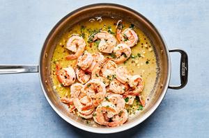 lemon juice & parsley being stirred into shrimp scampi in a skillet