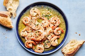 homemade shrimp scampi on a serving plate surrounded by crusty bread