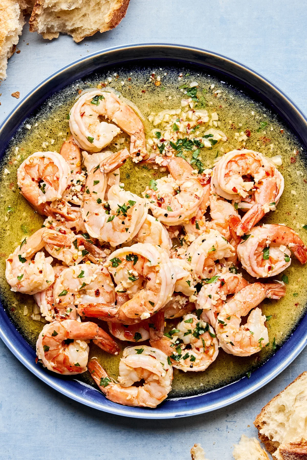 shrimp scampi on a plate made with butter, olive oil, wine, salt, red pepper flakes, black pepper, parsley & lemon juice