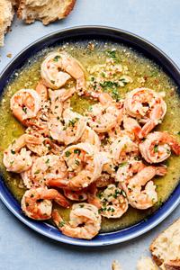 shrimp scampi on a plate made with butter, olive oil, wine, salt, red pepper flakes, black pepper, parsley & lemon juice