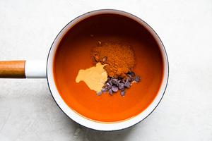 enchilada sauce, chocolate, peanut butter and chili powder in a sauce pan