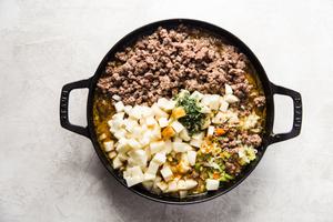 ground lamb, potatoes and vegetables in a skillet for a lamb pot pie