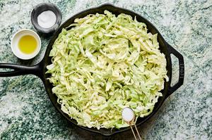 shredded cabbage tossed with olive oil and seasoned with salt in a cast iron skillet
