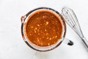 Slow Cooker Barbacoa Beef in a measuring cup with a whisk