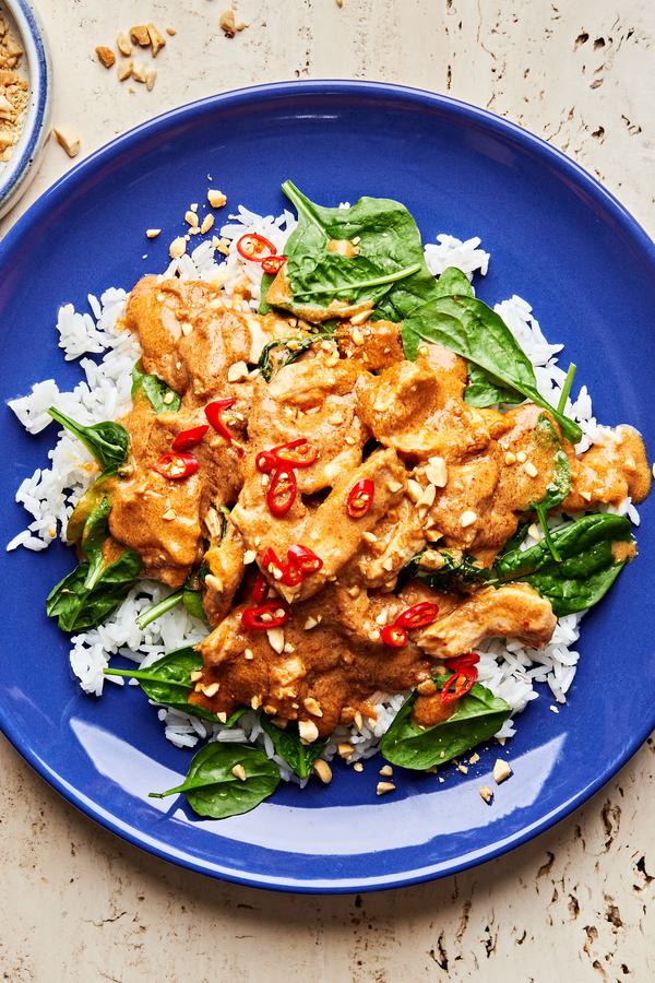 slow cooker swimming rama served on top of white rice topped with crushed peanuts, basil and red chili flakes