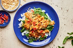 slow cooker swimming rama served on top of white rice topped with crushed peanuts, basil and red chili flakes