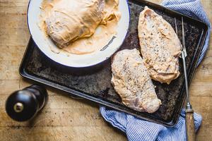2 chicken breasts on a baking sheet marinated with chipotle mayonnaise