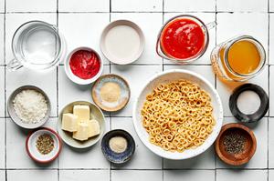 pasta, tomato paste, butter, spices, tomato sauce, chicken stock, heavy cream and Parmesan in prep bowls to make spaghettios