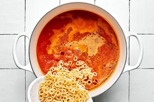 O shaped pasta noodles being added to homemade spaghettiO sauce