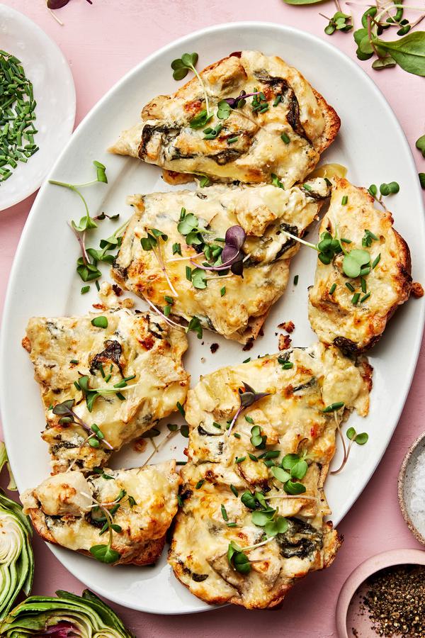 homemade spinach artichoke bread cut into slices on a serving plate