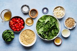 spinach, orzo, tomatoes, basil, feta, pine nuts and spices in prep bowls to make spinach orzo salad and basil dressing