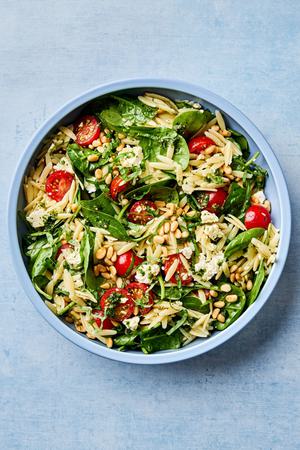 Spinach Orzo Salad With Feta Tomatoes and a Basil Dressing topped with basil and pine nuts