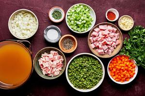 peas, onion, celery, carrots, parsley, ham, bacon, chicken stock and spices in prep bowls for split pea soup