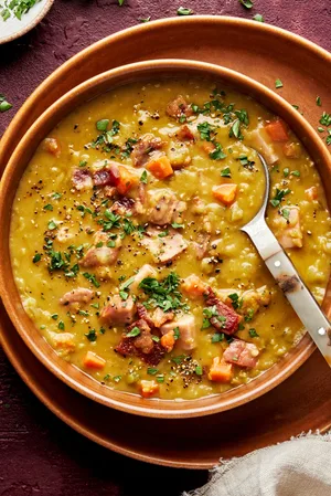 a bowl of homemade split pea soup with ham and bacon sprinkled with fresh parsley