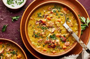 a bowl of homemade split pea soup made with ham, bacon, celery, onion and carrots topped with fresh parsley