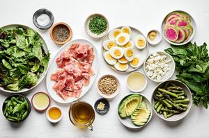 greens, pancetta, boiled egg, asparagus, watermelon radish, goat cheese and ingredients for herb vinaigrette in bowls