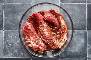 flank steak marinating in fish sauce, pepper, soy sauce, vegetable oil, ginger, lime zest, lime juice, chili flakes & garlic