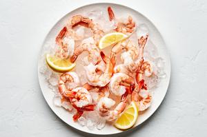 Steamed shrimp on top of ice on a serving platter garnished with lemon wedges