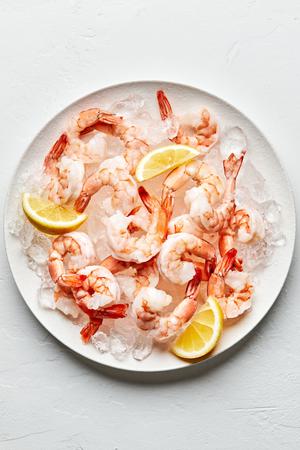 Steamed shrimp on top of ice on a serving platter garnished with lemon wedges