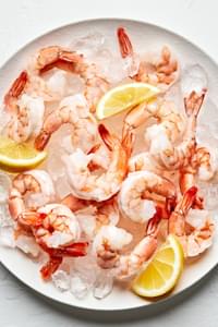 Steamed shrimp on top of ice on a serving platter garnished with lemon wedges