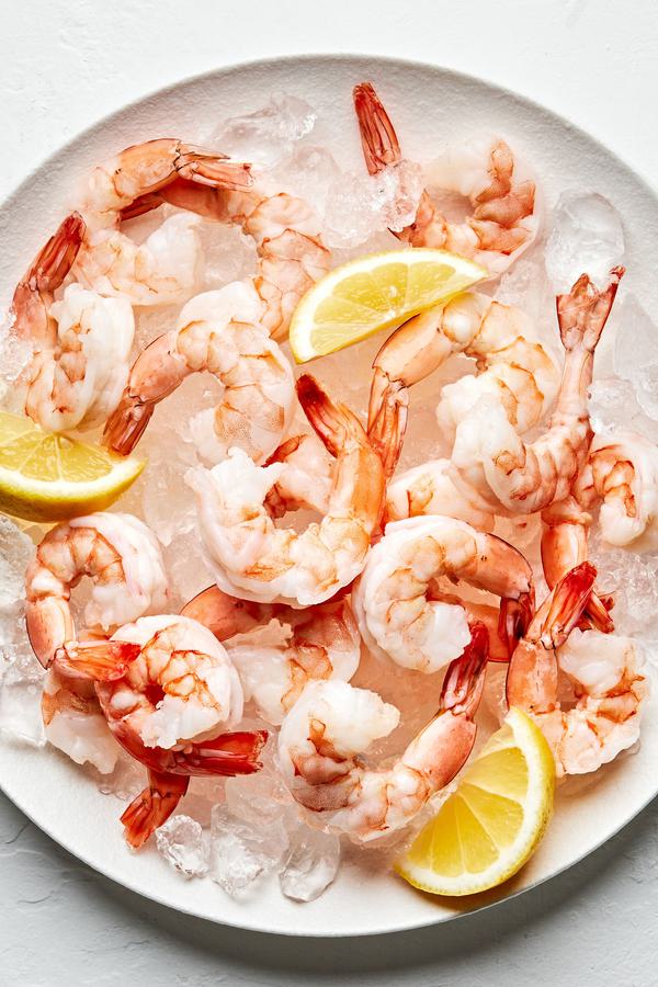 Steamed shrimp on top of ice on a serving platter garnished with lemon wedges