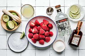 sugar, frozen strawberries, tequila, lime juice, orange liqueur, salt and lime wedges in prep bowls for strawberry margaritas