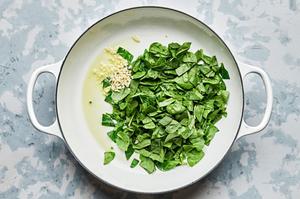spinach and garlic being cooked in olive oil in a skillet