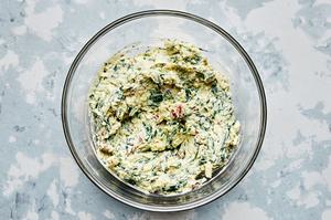 cooked spinach, garlic, cream cheese, mozzarella, sun-dried tomatoes, and pesto stirred together in a mixing bowl
