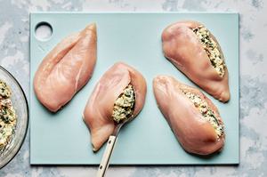 chicken breast being stuffed with spinach, garlic, cream cheese, mozzarella, sun-dried tomatoes, and pesto
