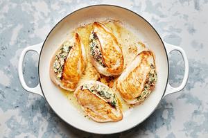 chicken breast stuffed with spinach, garlic, cream cheese, mozzarella, sun-dried tomatoes and pesto being cooked in a skillet