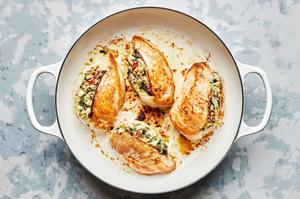 chicken breast stuffed with spinach, garlic, cream cheese, mozzarella, sun-dried tomatoes and pesto being cooked in a skillet