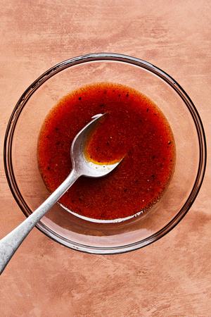 honey, lime juice, spices and olive oil being stirred in a bowl with a spoon