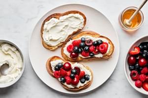 sweet berry bruschetta being assembled with challah, mascarpone/yogurt whip, fresh berries and honey