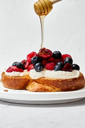 sweet berry bruschetta made with challah, whipped mascarpone and yogurt & berries being drizzled with honey