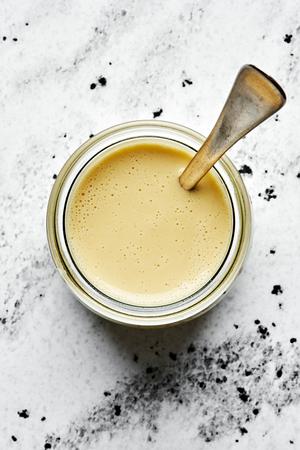 homemade tahini dressing in a jar with a spoon made with tahini, olive oil, apple cider vinegar,, sesame oil, honey & spices
