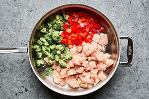 diced chicken, broccoli and red pepper being cooked in vegetable oil in a skillet