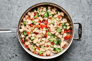 diced chicken, broccoli and red pepper being cooked in vegetable oil in a skillet