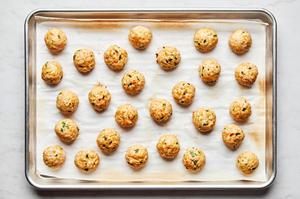 meatballs made with ground chicken, eggs, panko, spices, green onions, and sesame oil on a parchment lined baking sheet
