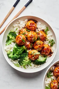 homemade teriyaki meatballs served over white rice with steamed broccoli next to chopsticks