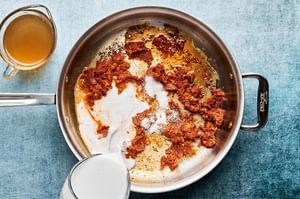A pan of Thai red curry sauce simmering on the stove, made with coconut milk and red curry paste