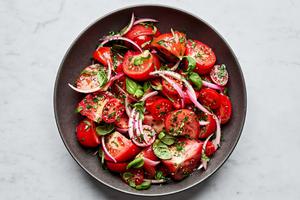 tomato salad made with marinated onions, tomatoes, olive oil, salt, parsley, basil, garlic, onion and vinegar.