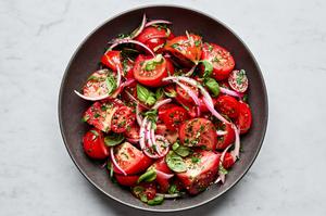 tomato salad made with marinated onions, tomatoes, olive oil, salt, parsley, basil, garlic, onion and vinegar.