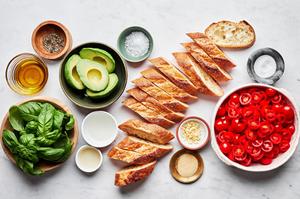 sliced baguette, cherry tomatoes, avocado, basil, olive oil, salt, pepper, garlic, balsamic vinegar and lemon juice in bowls