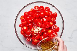 tomatoes, olive oil, balsamic vinegar and garlic being combined in a bowl