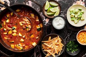 chicken tortilla surrounded by tortilla strips, cilantro, sour cream, cheese, avocado and lime juice for topping