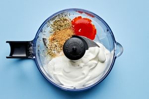 lime crema being made in a blender with sour cream, lime juice, oregano, salt, cumin, garlic powder, tapatio & milk