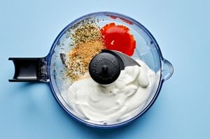 lime crema being made in a blender with sour cream, lime juice, oregano, salt, cumin, garlic powder, tapatio & milk