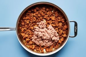 chorizo and refried beans being cooked together in a skillet