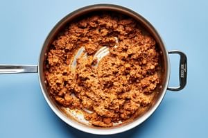 chorizo and refried beans being stirred together in a skillet