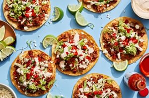 Easy tostadas with chorizo, refried beans, lettuce, cotija, pico de gallo, guac, and lime crema on crispy shells